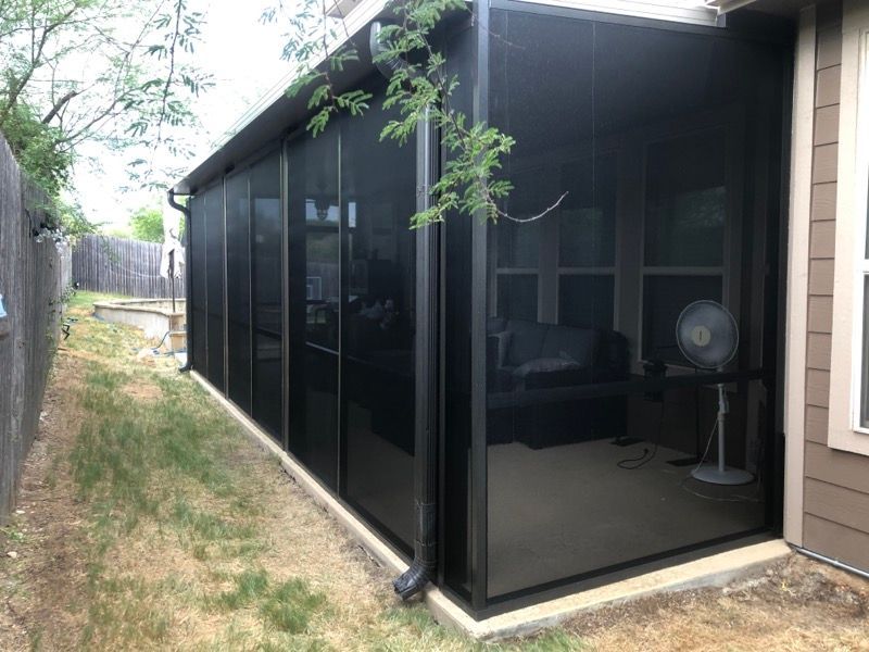 A screened in porch in the backyard of a house.