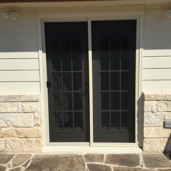 A sliding glass door with a screen is on the side of a house.