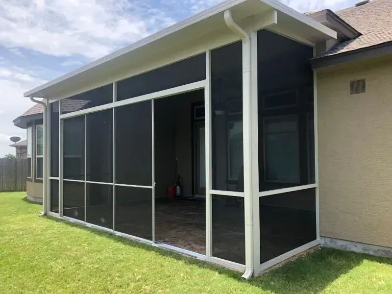 A screened in porch on the side of a house.