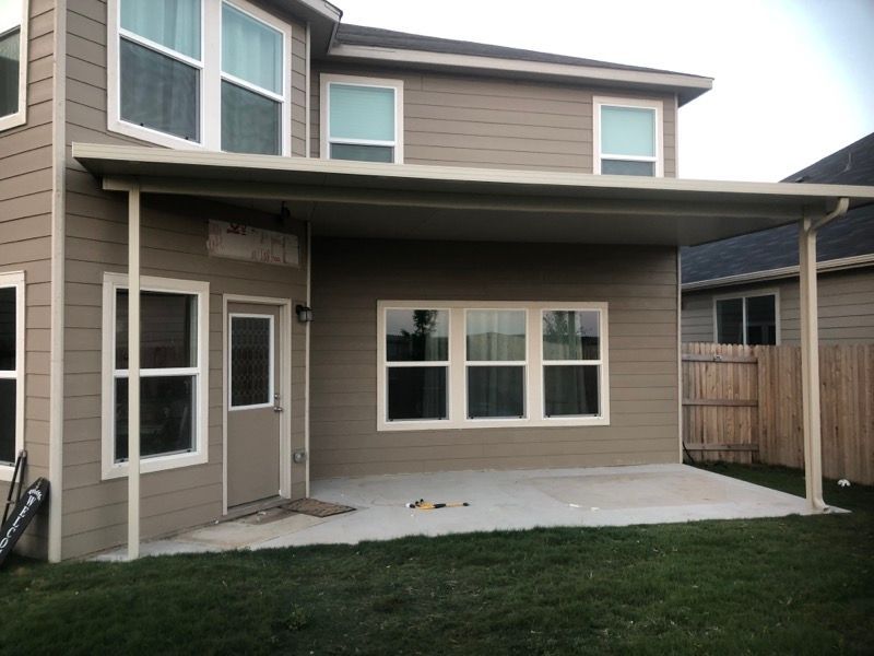 The back of a house with a covered patio and a fence.