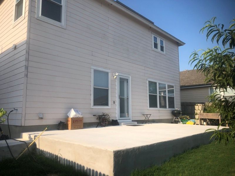 A large white house with a concrete deck in front of it.