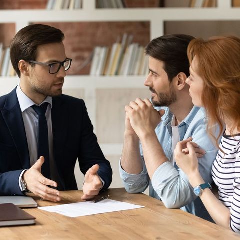 A man and a woman are sitting at a table talking to each other.