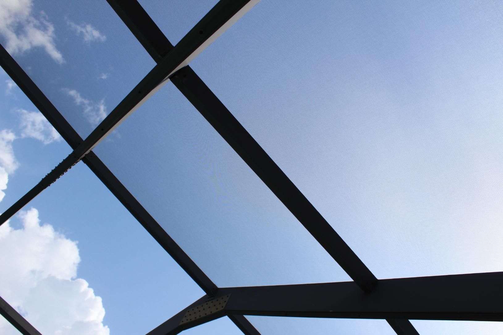 Looking up at a blue sky through a glass roof.