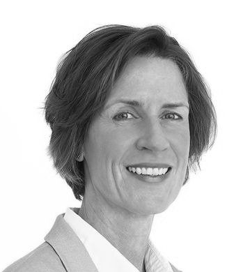 Lachende vrouw met kort bruin haar, gekleed in een blazer.