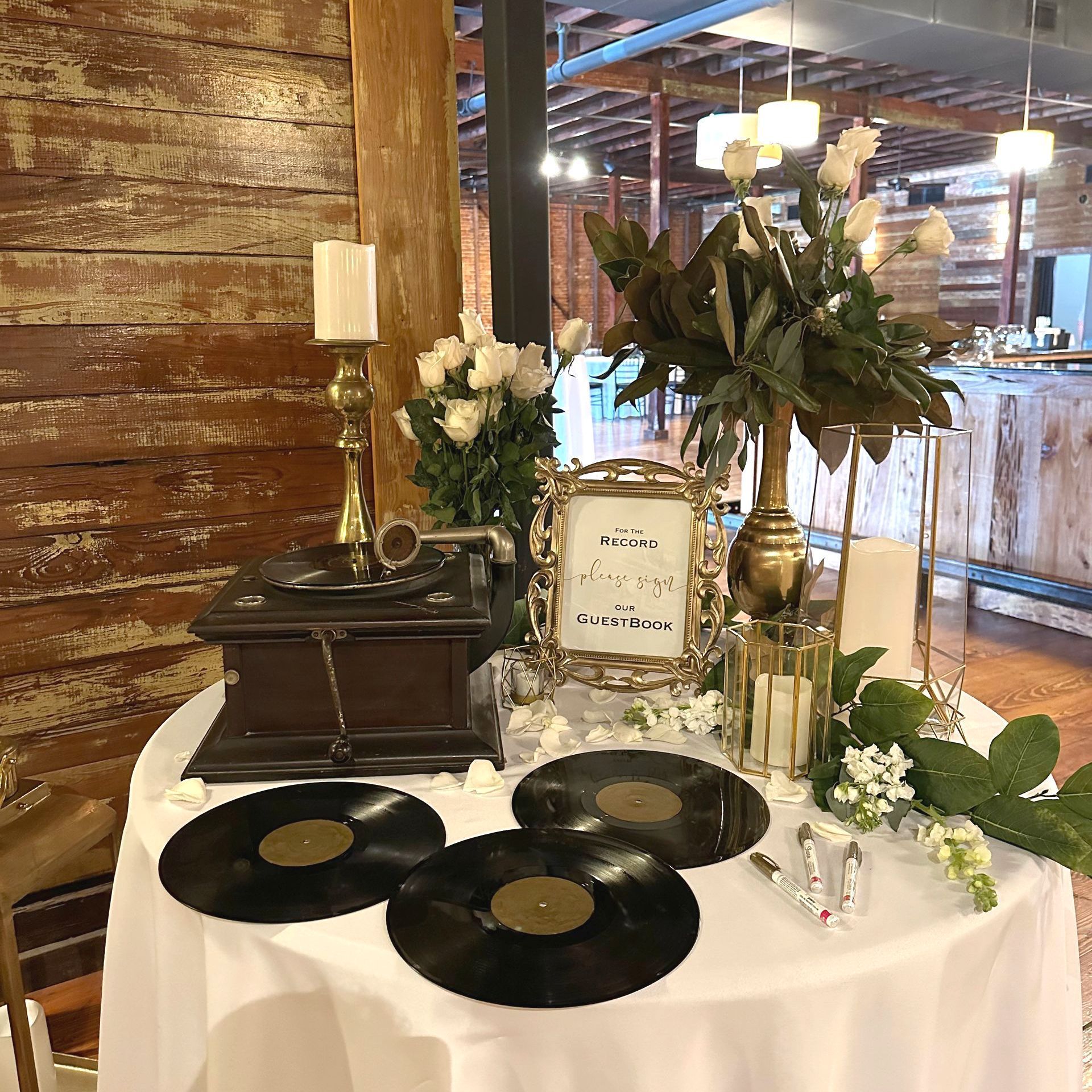 A table with a gramophone , candles , flowers and records on it.