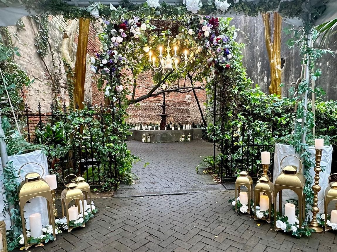 A brick walkway leading to a wedding ceremony with candles and flowers.