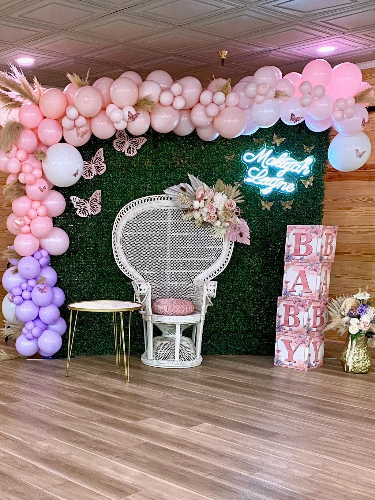 A room decorated with pink and purple balloons and a peacock chair.