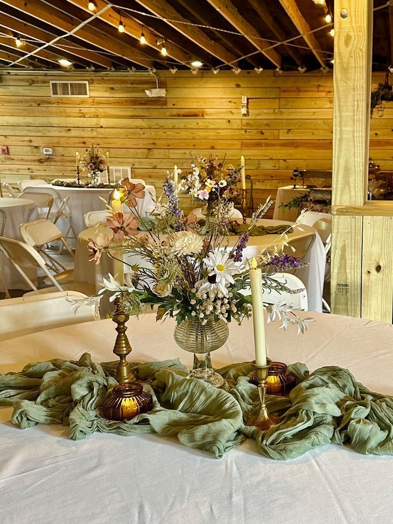 A table with a vase of flowers and candles on it.