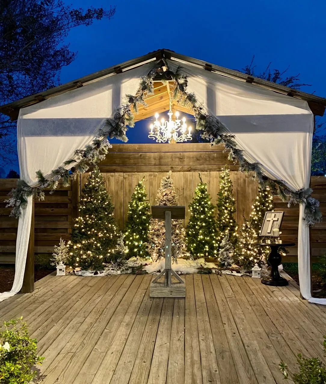 A wooden deck with christmas trees and a chandelier.