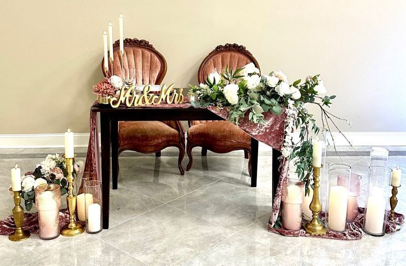 A couple of chairs sitting next to a table with candles and flowers on it.