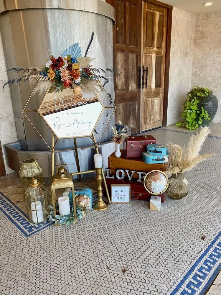 A display of luggage , candles , lanterns and flowers in front of a building.