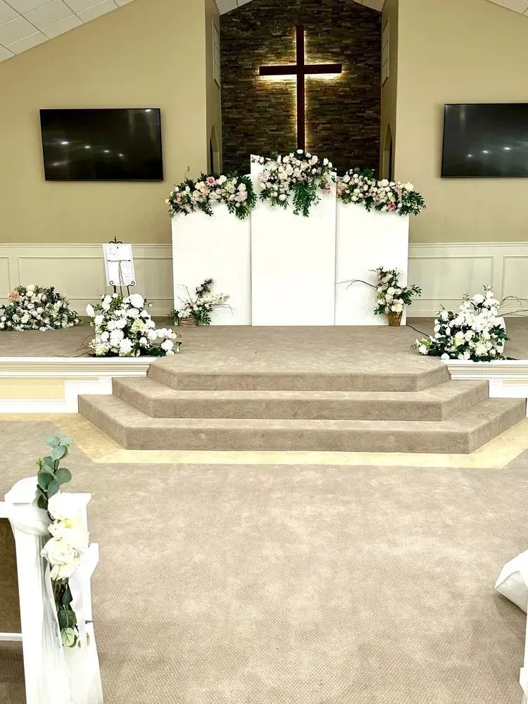 A church filled with flowers and a cross on the altar.