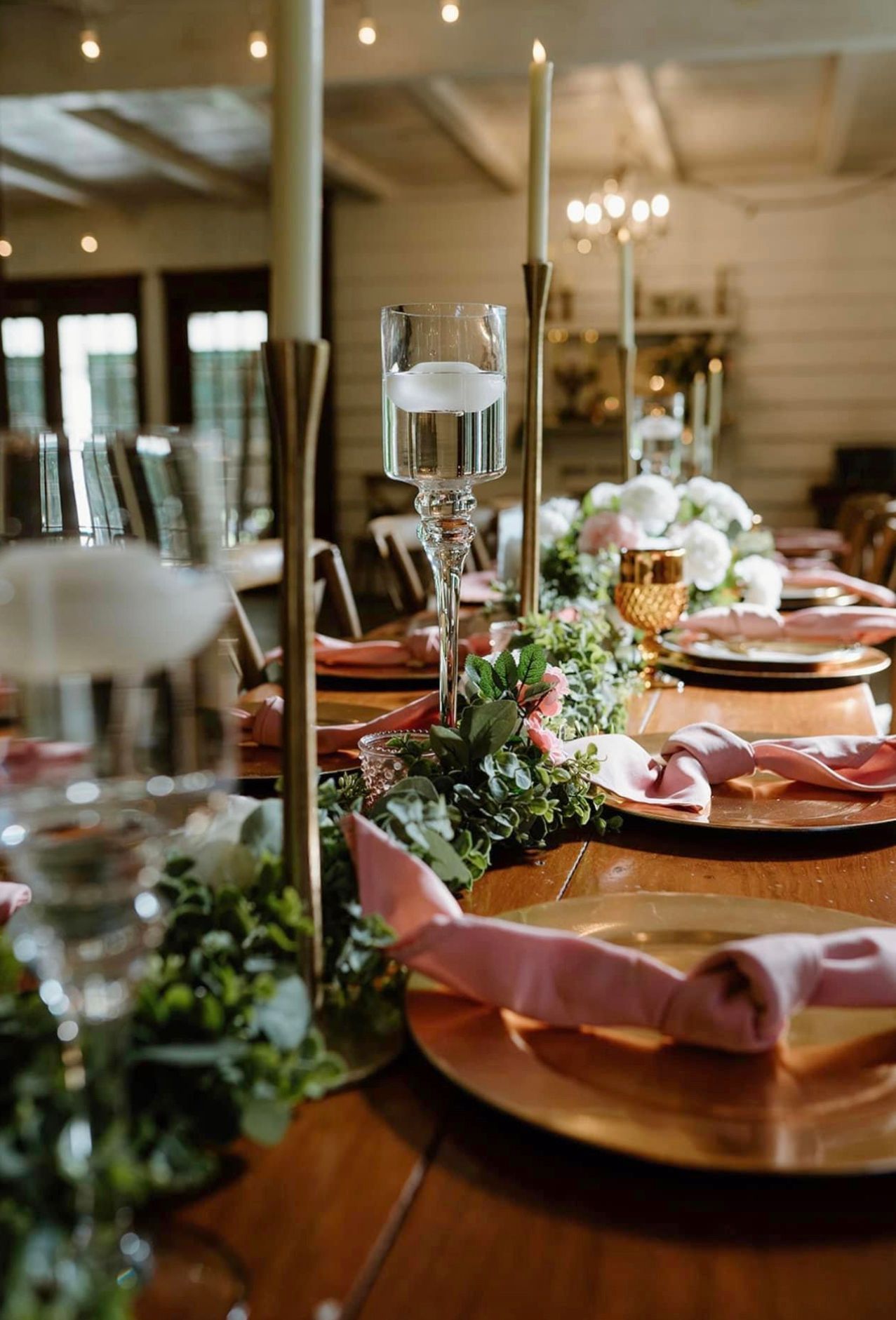 A table set for a wedding reception with plates , candles , and glasses.