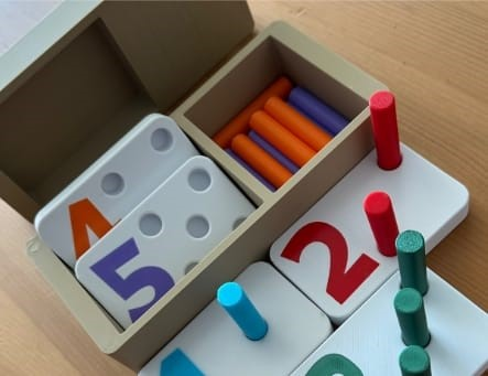 Juguete de madera para aprender números, con clavijas de colores y fichas numéricas.