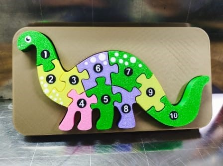 Puzzle de dinosaurio de 10 piezas en varios colores, sobre fondo marrón.