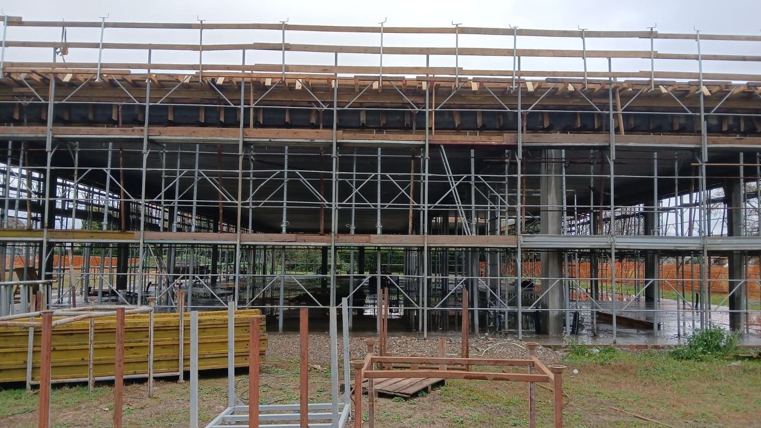 Persone che lavorano a un tavolo su progetti di case con un computer portatile, attrezzi e planimetrie arrotolate.