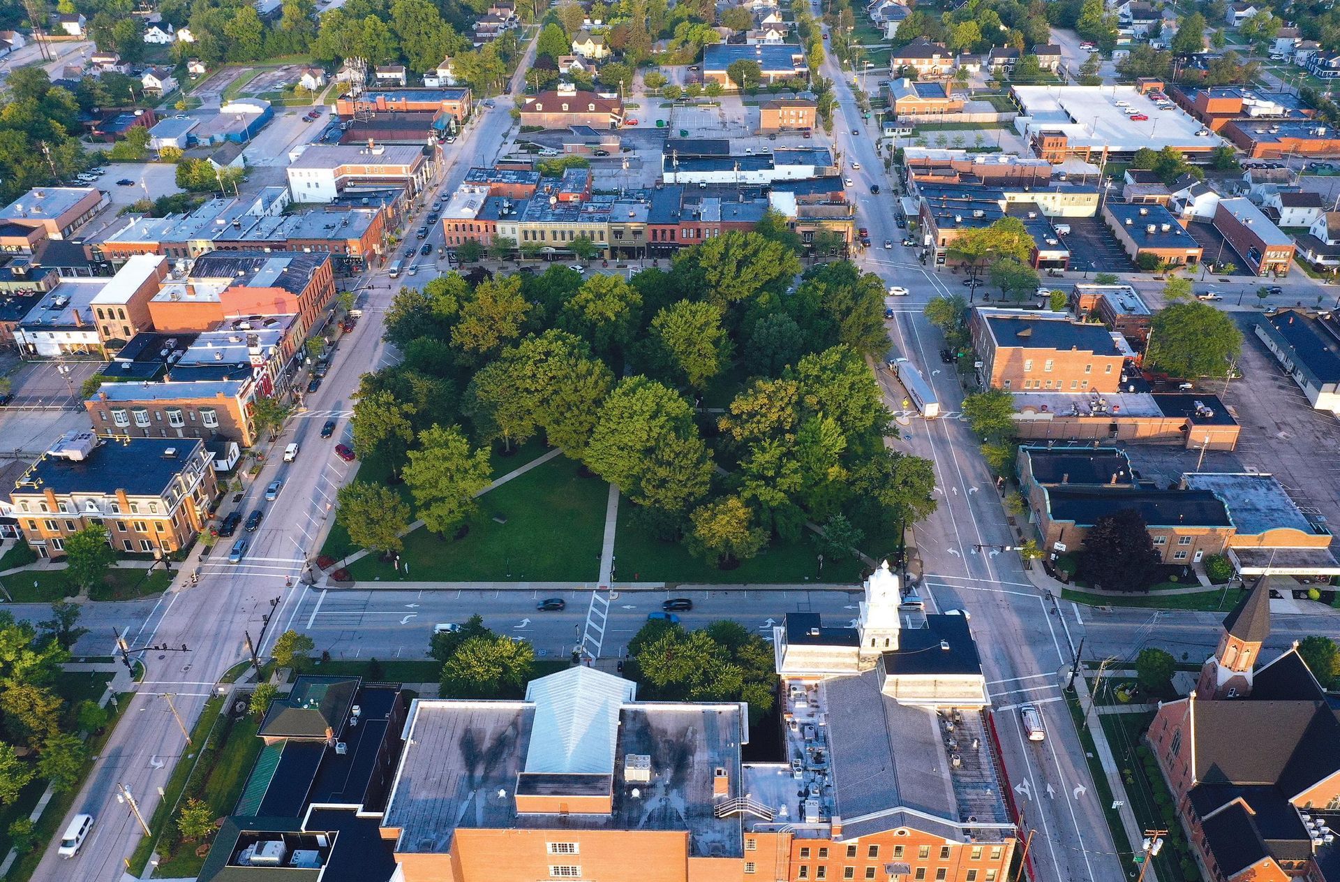 Aerial view of a town square with buildings, trees, and roads.