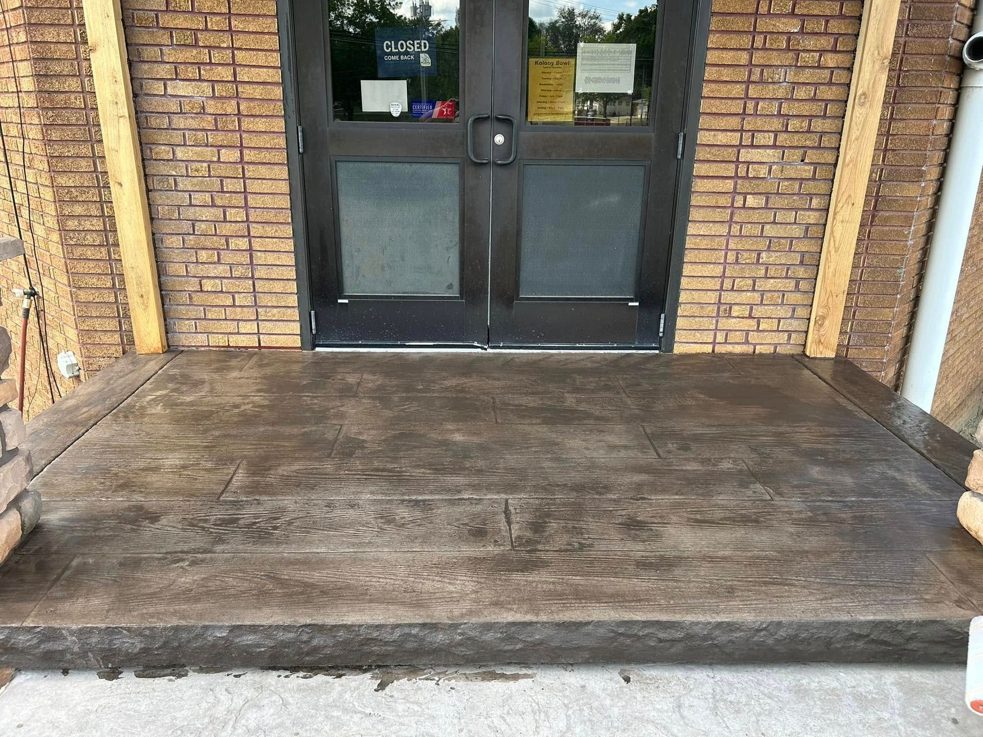 Exterior view of a building's entrance featuring a concrete ramp and double doors.