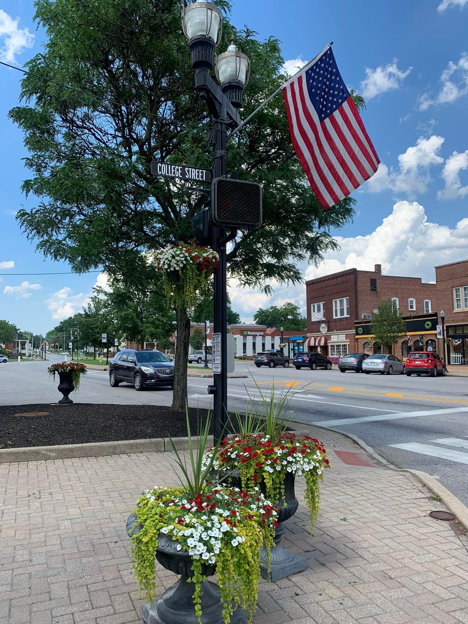 Street scene with brick planters, American flag, street lamp, and buildings.