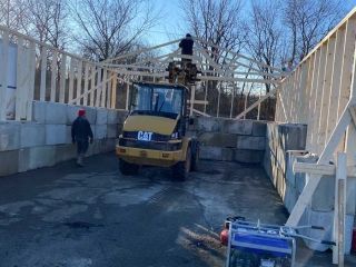 Construction site: Workers building a wooden structure, with a forklift and concrete blocks.