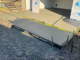 Freshly poured concrete ramp and landing, construction site. Yellow caution tape surrounds the area.