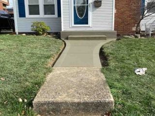 Concrete walkway and steps leading to a house entrance with a blue door.