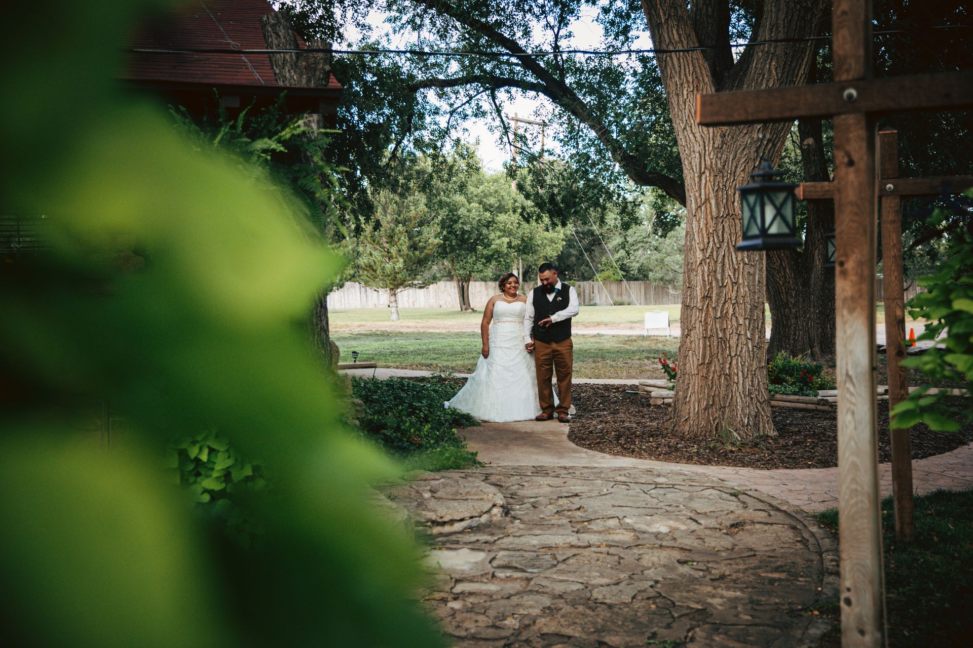 A bride and groom are standing next to each other in a park.