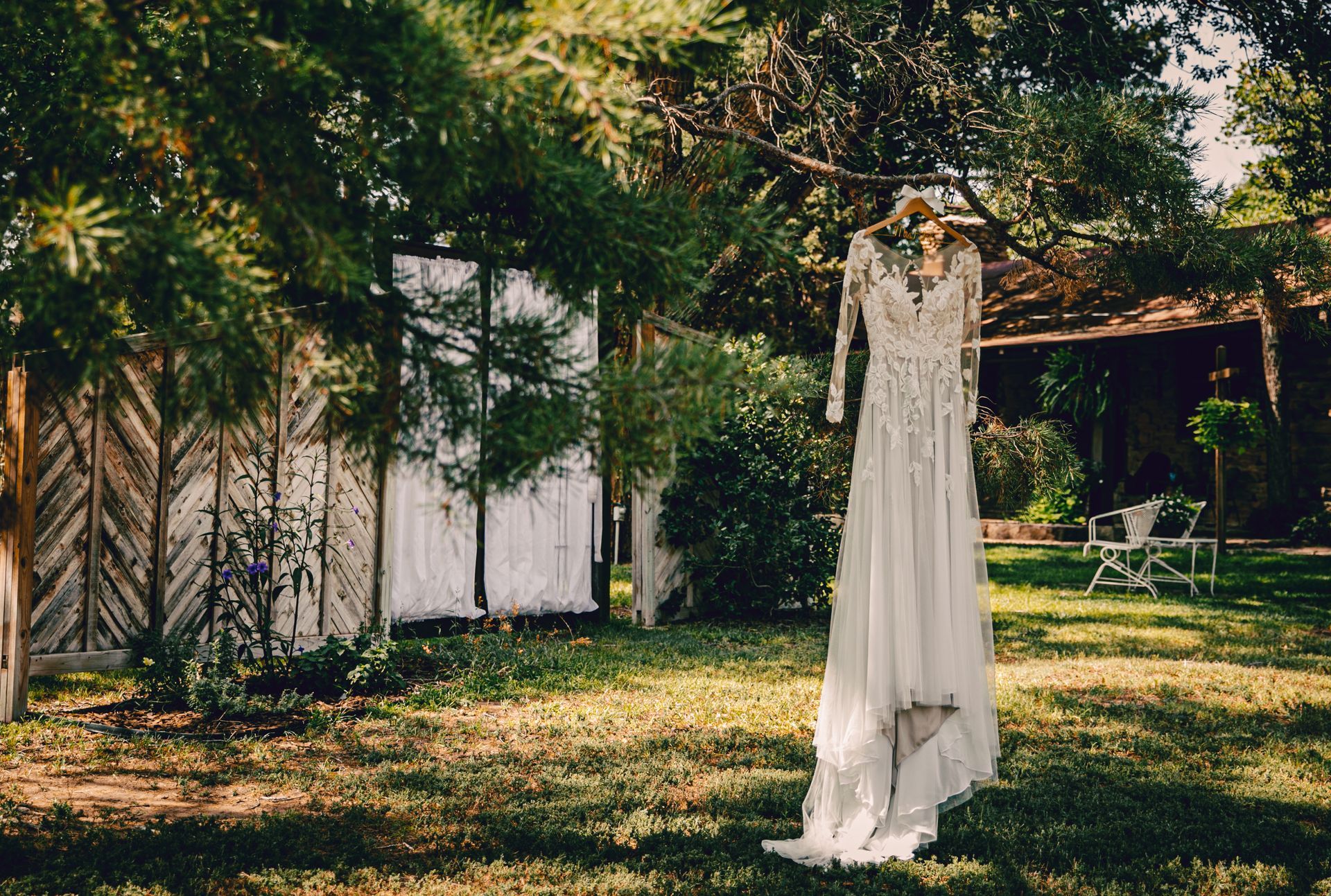 A wedding dress is hanging from a tree in a field.