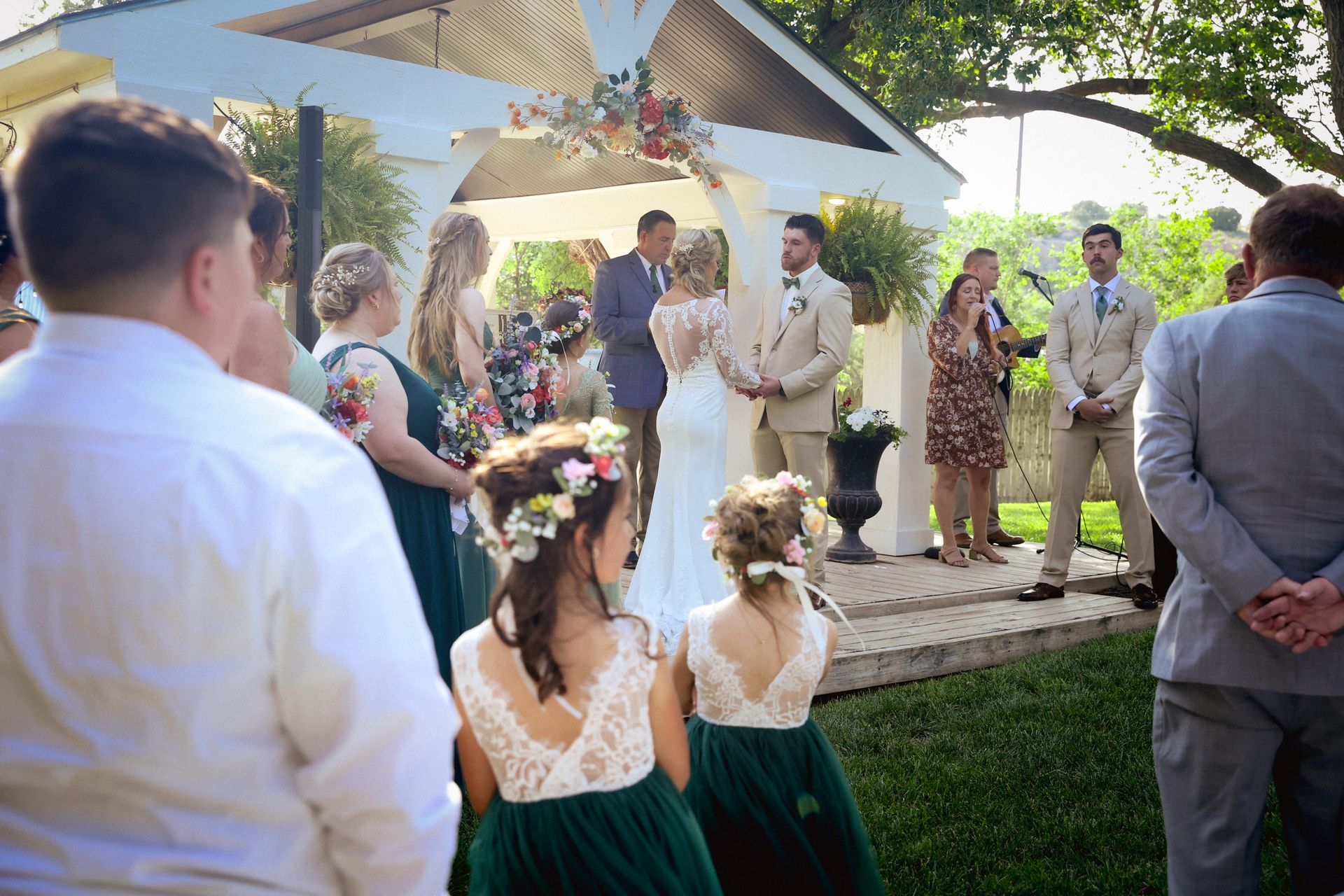 A wedding ceremony is taking place in the grass in front of a building.