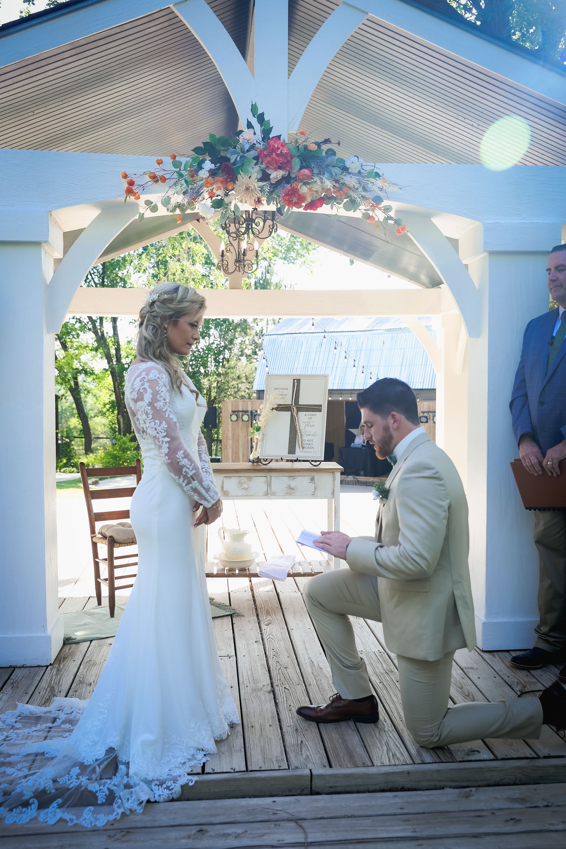 A bride and groom are kneeling down during their wedding ceremony.