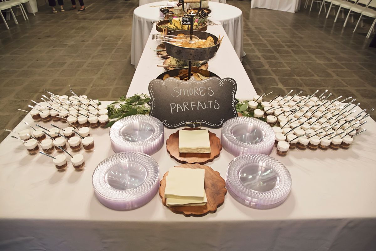 A long table with plates , cupcakes and a sign that says ' cupcakes parents ' on it.