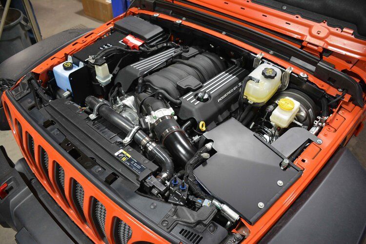 The engine of a jeep is shown with the hood open.