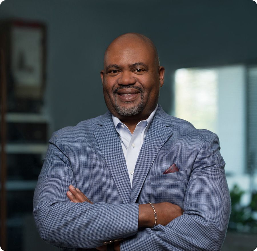 Man in blue blazer with arms crossed, smiling.