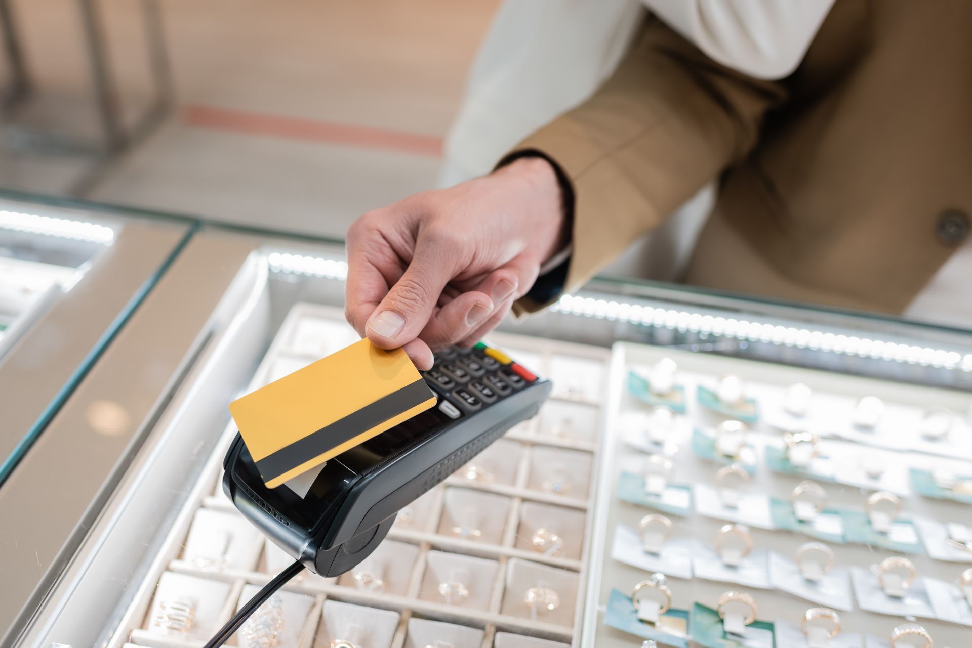 Person paying with a credit card at a jewelry store counter.
