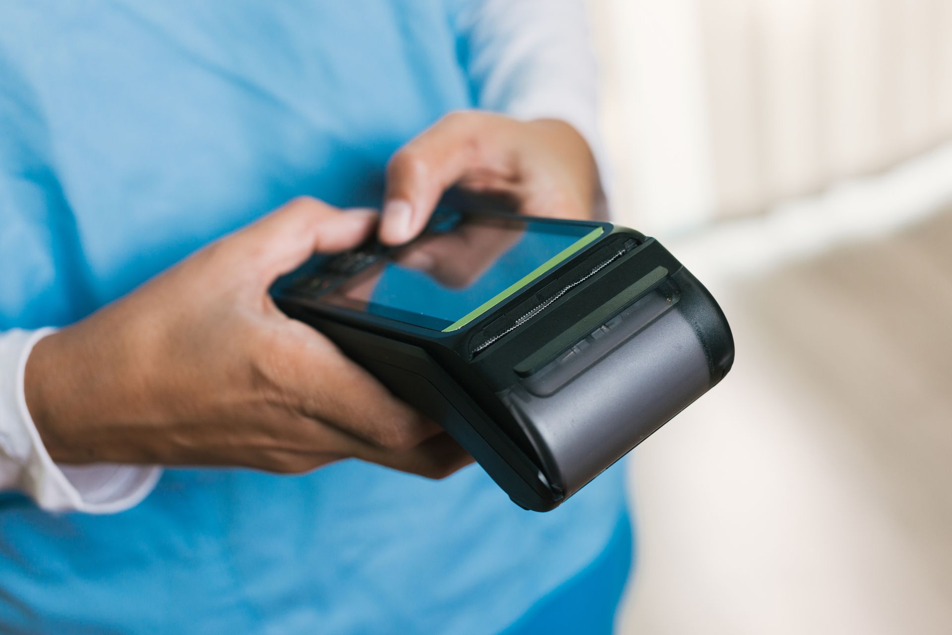 Person holding a black handheld credit card reader, possibly in a store.