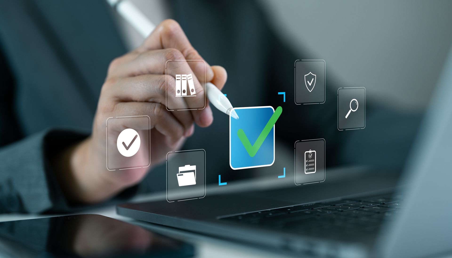 Person using a stylus to select a checkmark icon on a laptop screen, symbolizing approval.