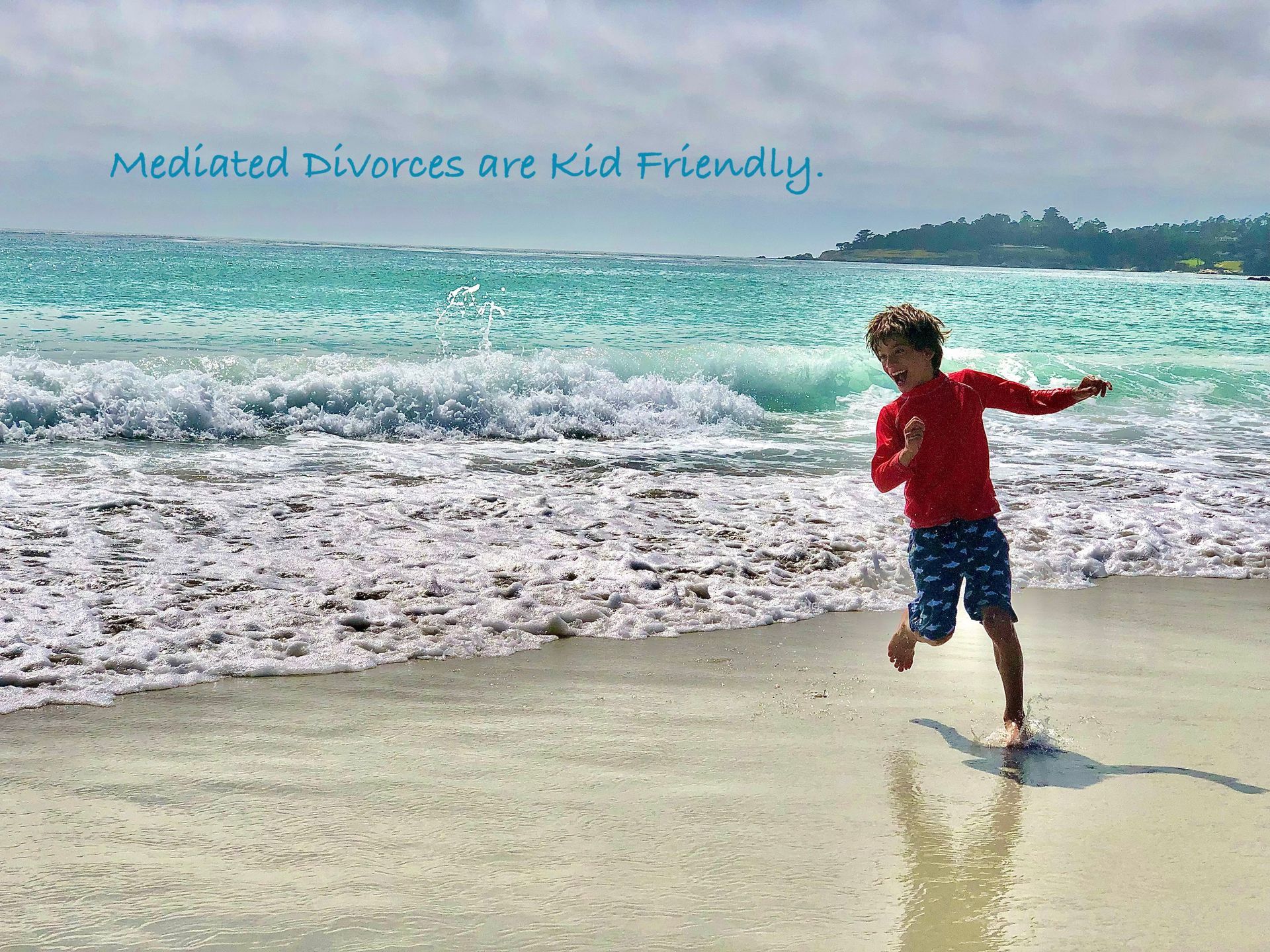A young boy is running on the beach near the ocean.