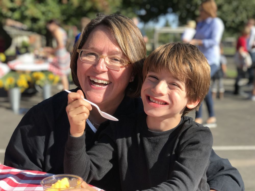 A woman and a boy are sitting at a table eating food.
