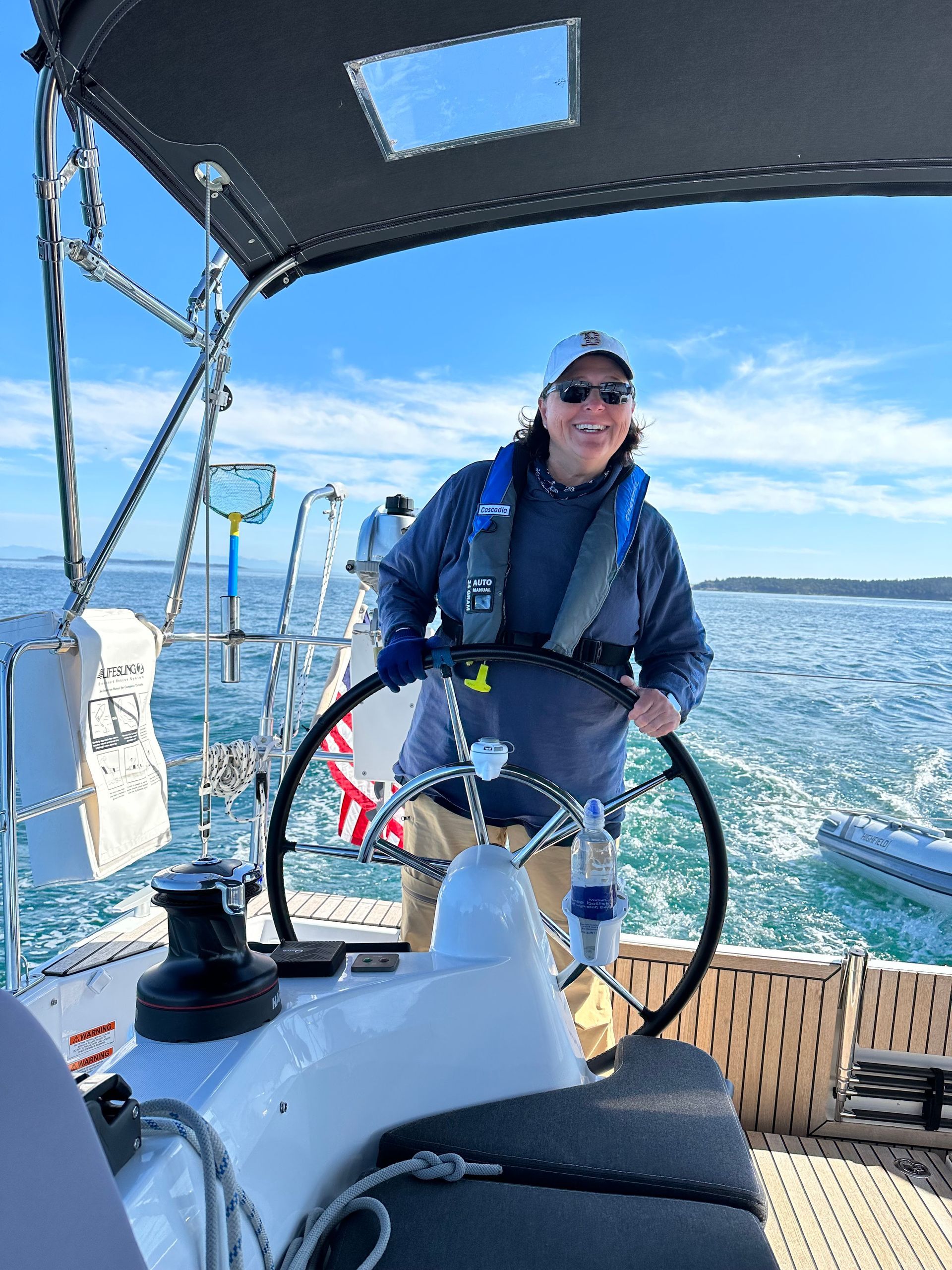 A man is steering a sailboat in the ocean.
