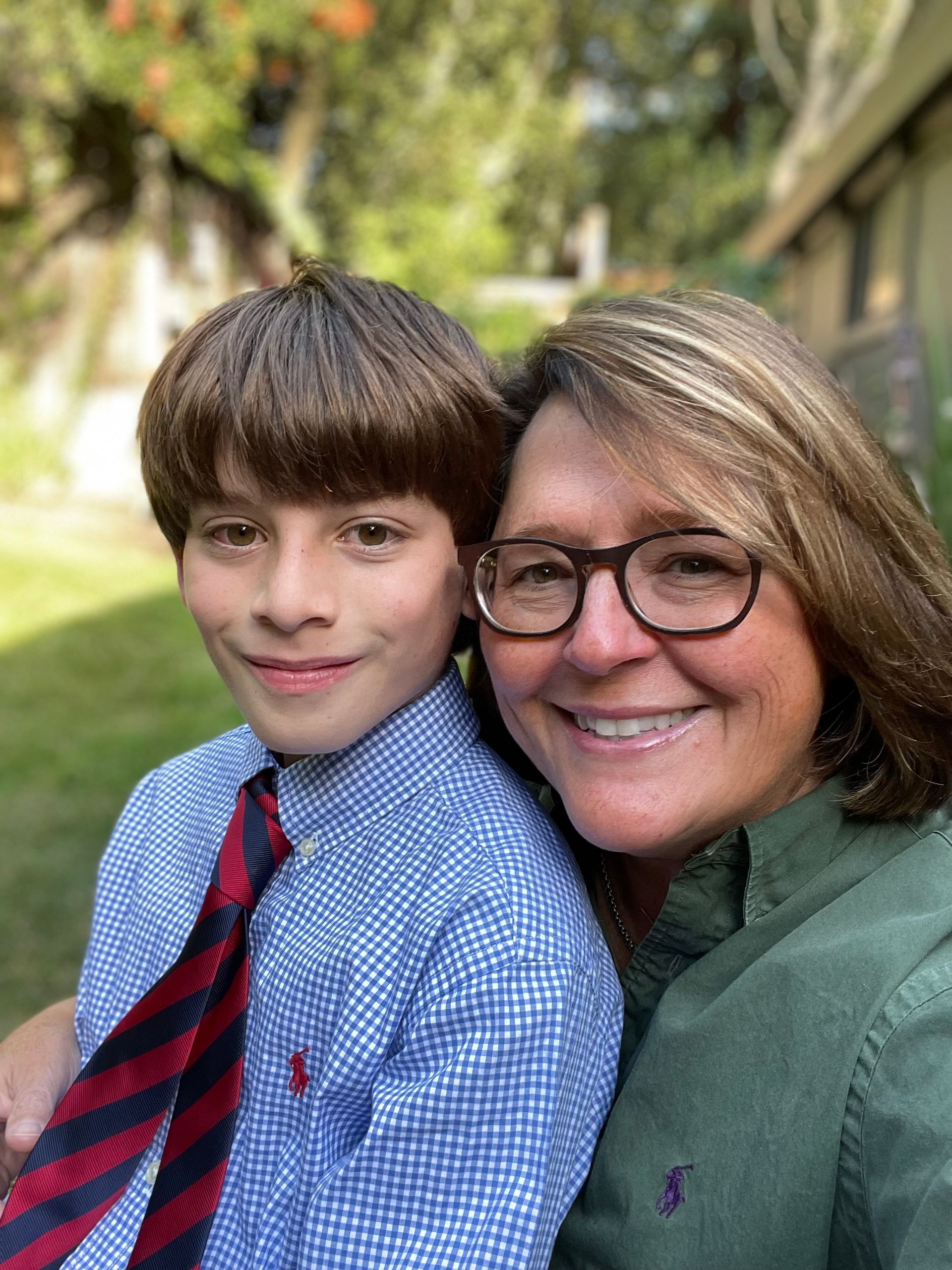 A woman and a boy are posing for a picture and the boy is wearing a tie.