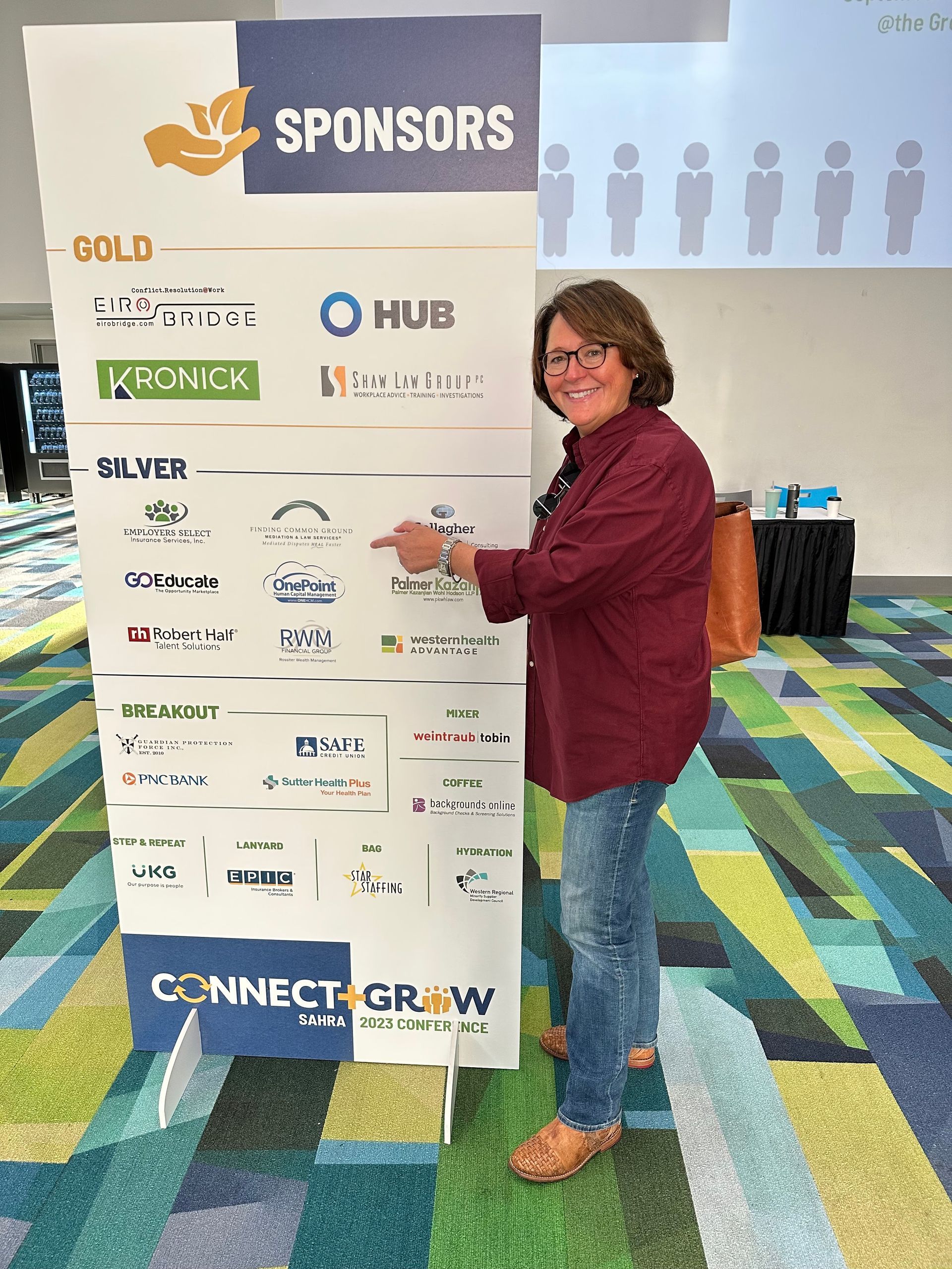 A woman is standing in front of a sign that says sponsors.