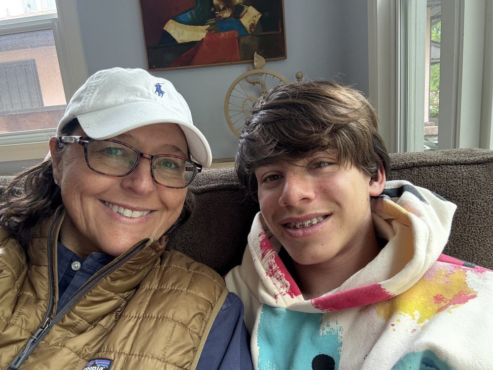A woman and a boy are posing for a picture while sitting on a couch.