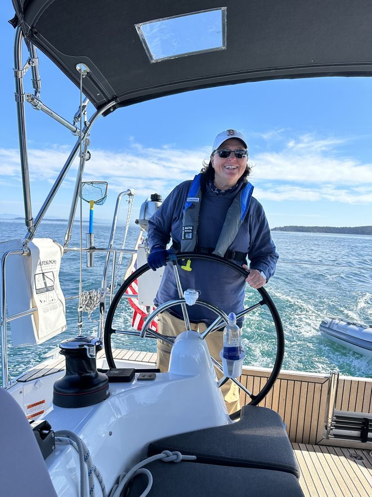 A man is steering a sailboat in the ocean.