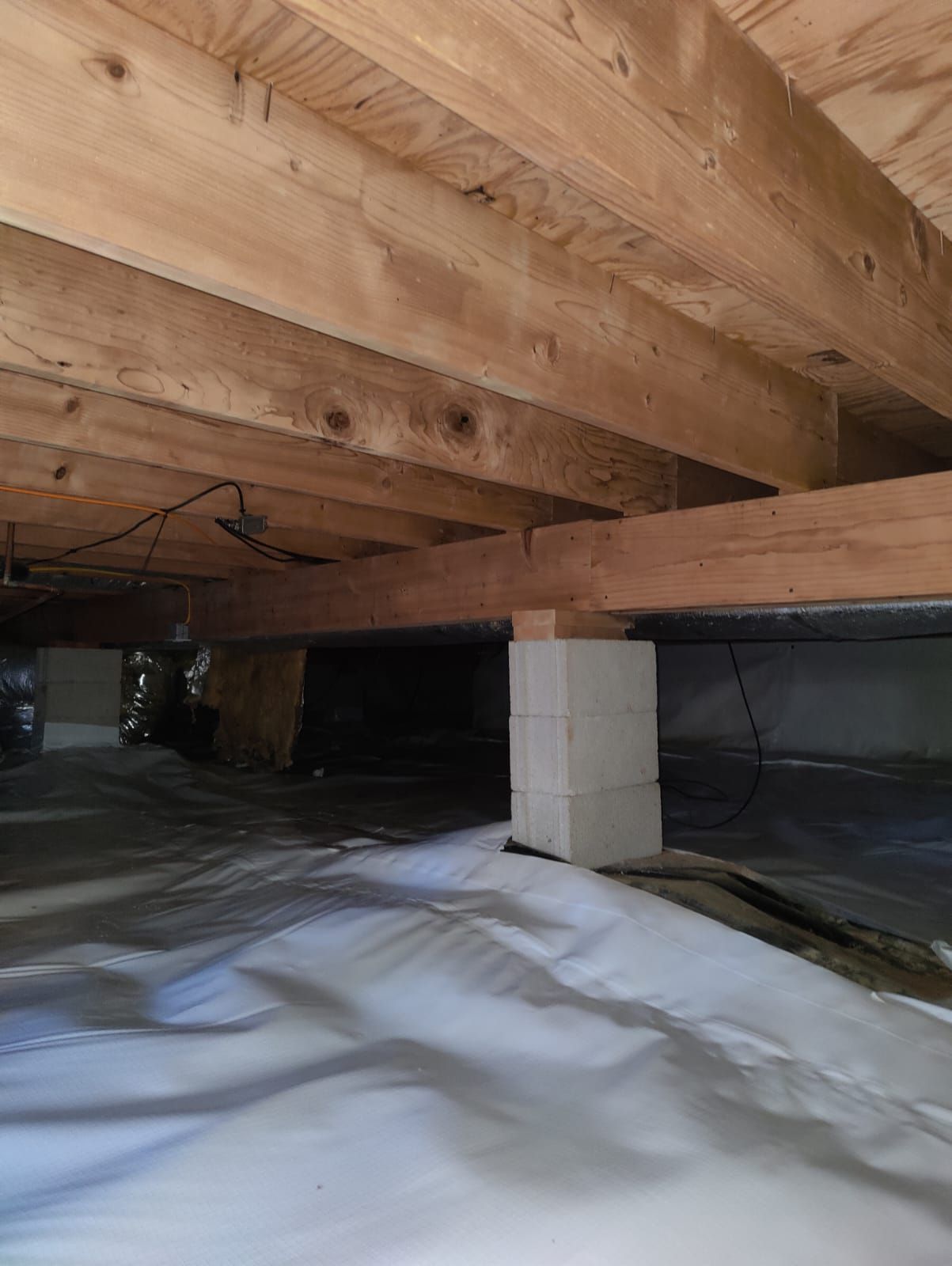 A wooden beam is sitting under a concrete wall in a basement.