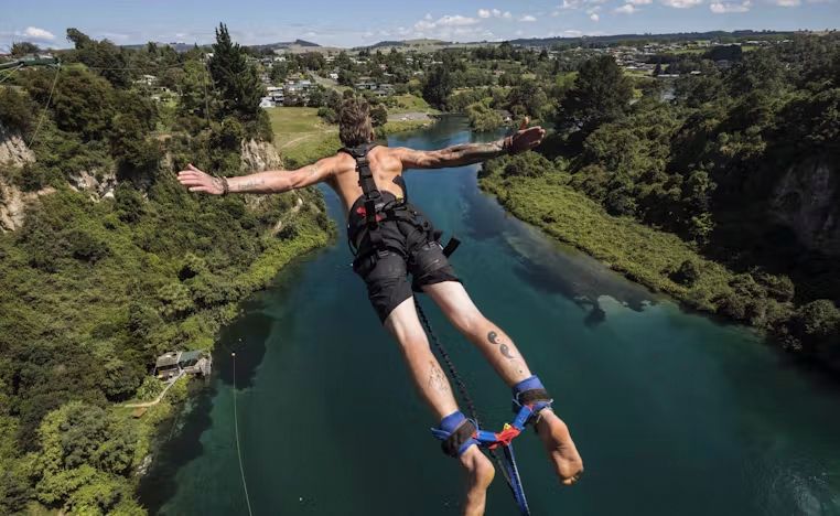 A man is jumping into a river with a bungee cord.