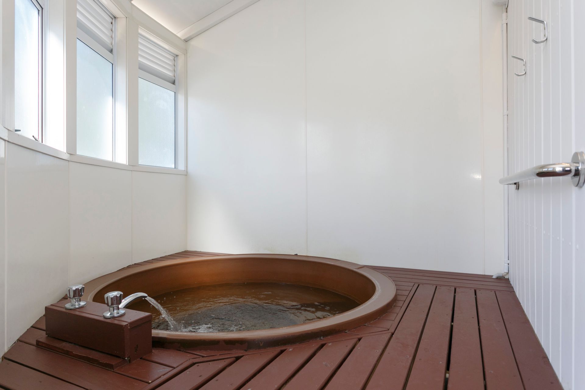 A round jacuzzi tub is sitting on a wooden floor in a bathroom.