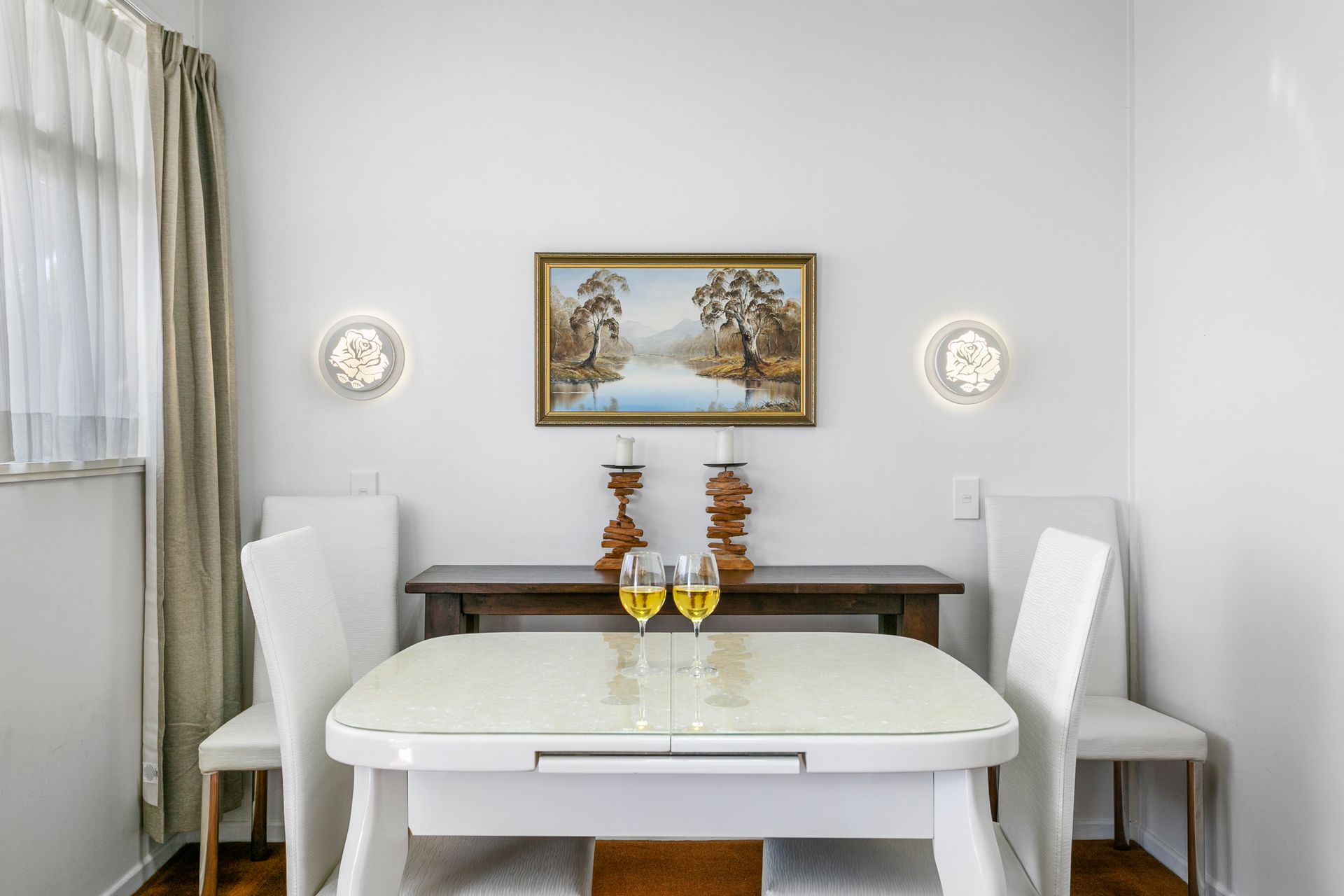 A dining room with a table and chairs and a painting on the wall.