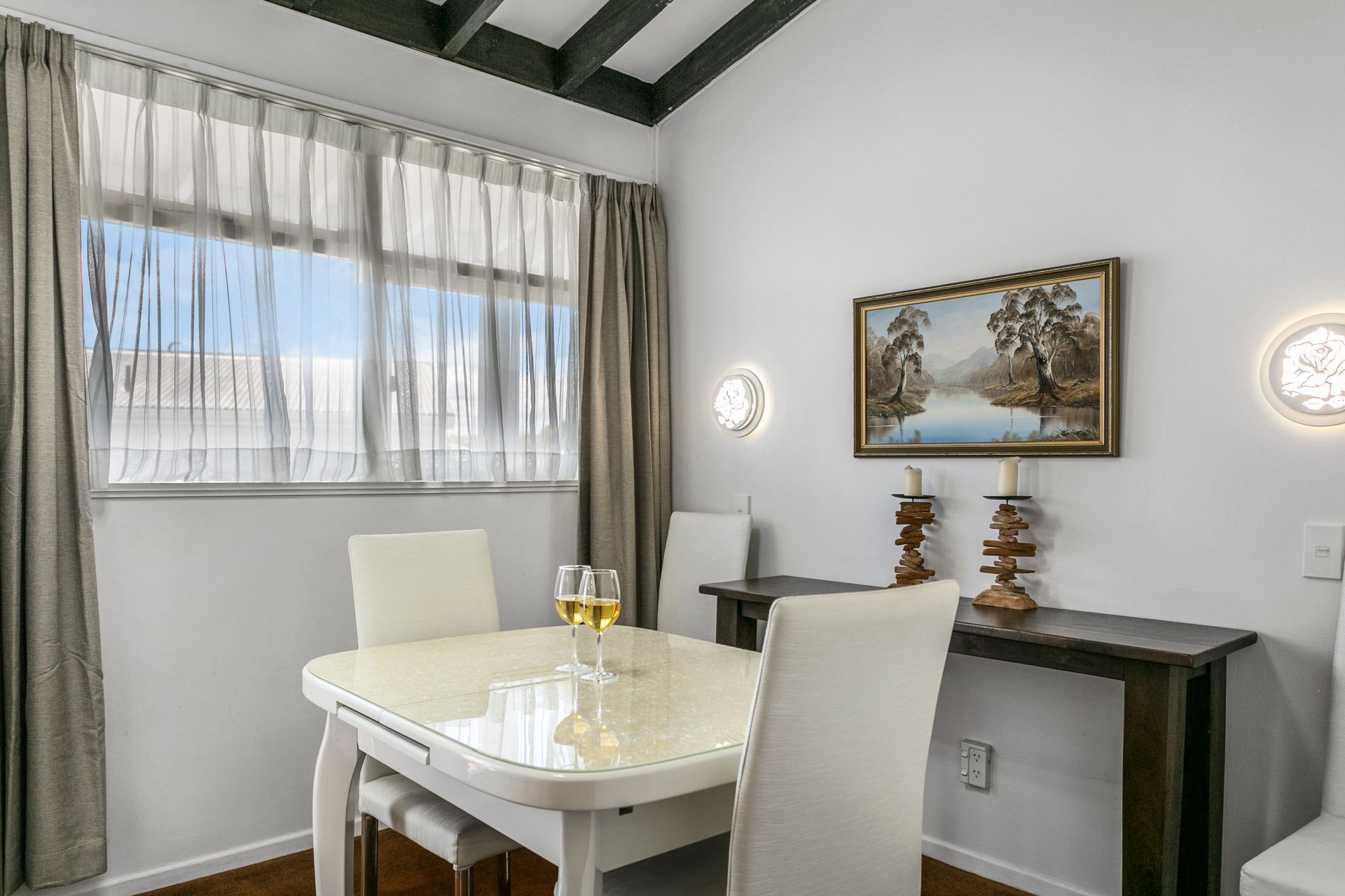A dining room with a table and chairs and a painting on the wall.