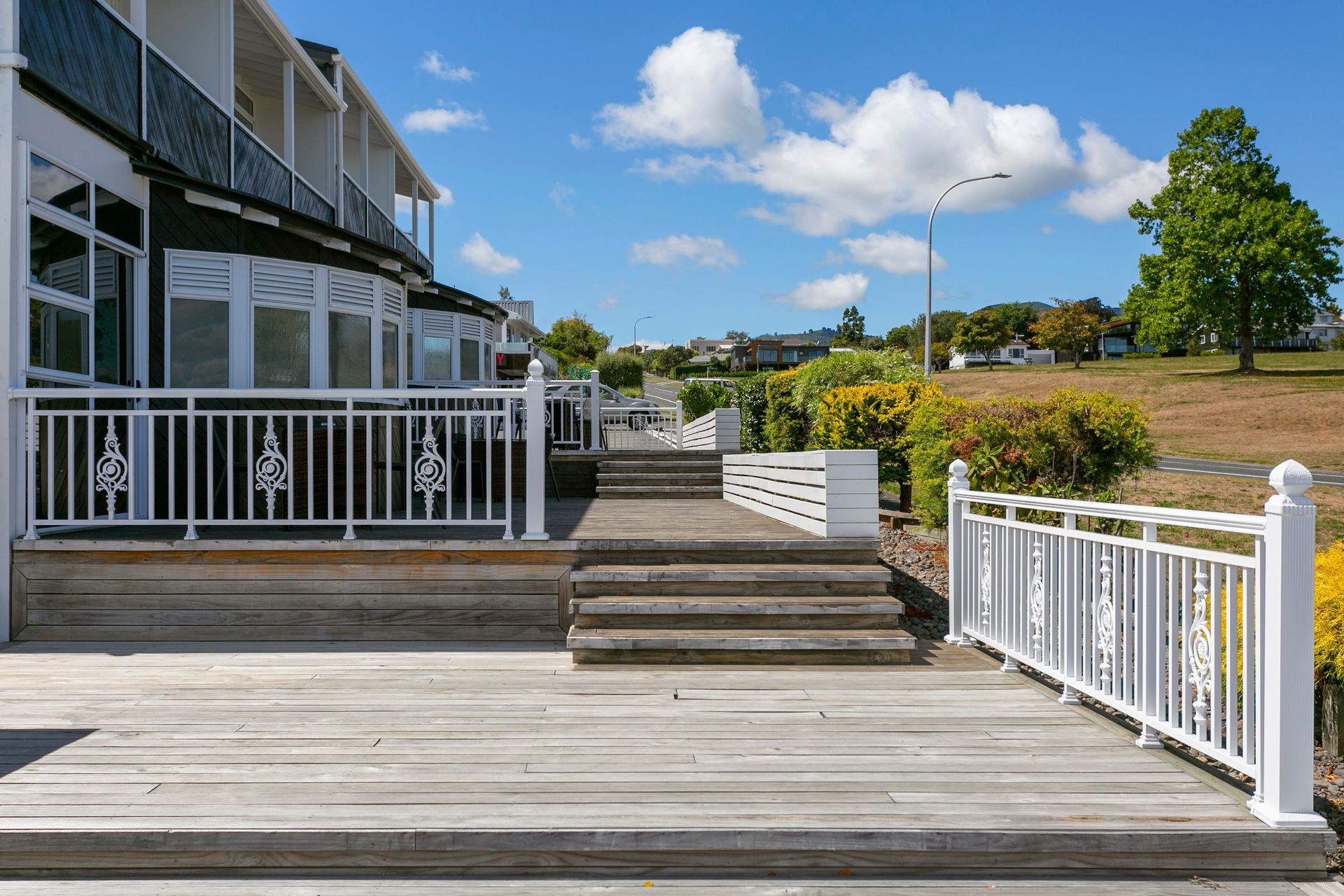 A wooden deck with stairs leading up to it and a white railing.