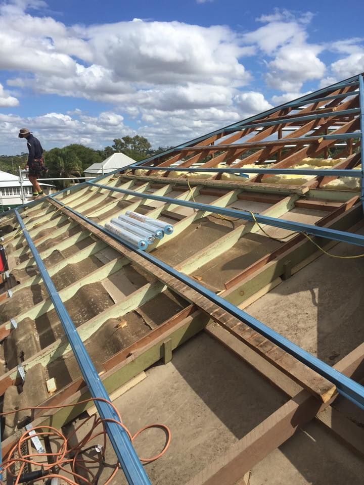 A Man is Standing on Top of a Wooden Roof — Bradshaw Plumbing & Roofing Pty Ltd In East Mackay, QLD A Man is Standing on Top of a Wooden Roof — Bradshaw Plumbing & Roofing Pty Ltd In East Mackay, QLD